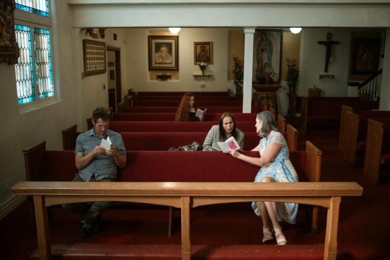 Interior view of a church with parishioners reading and conversing in pews, fostering a spiritual atmosphere.